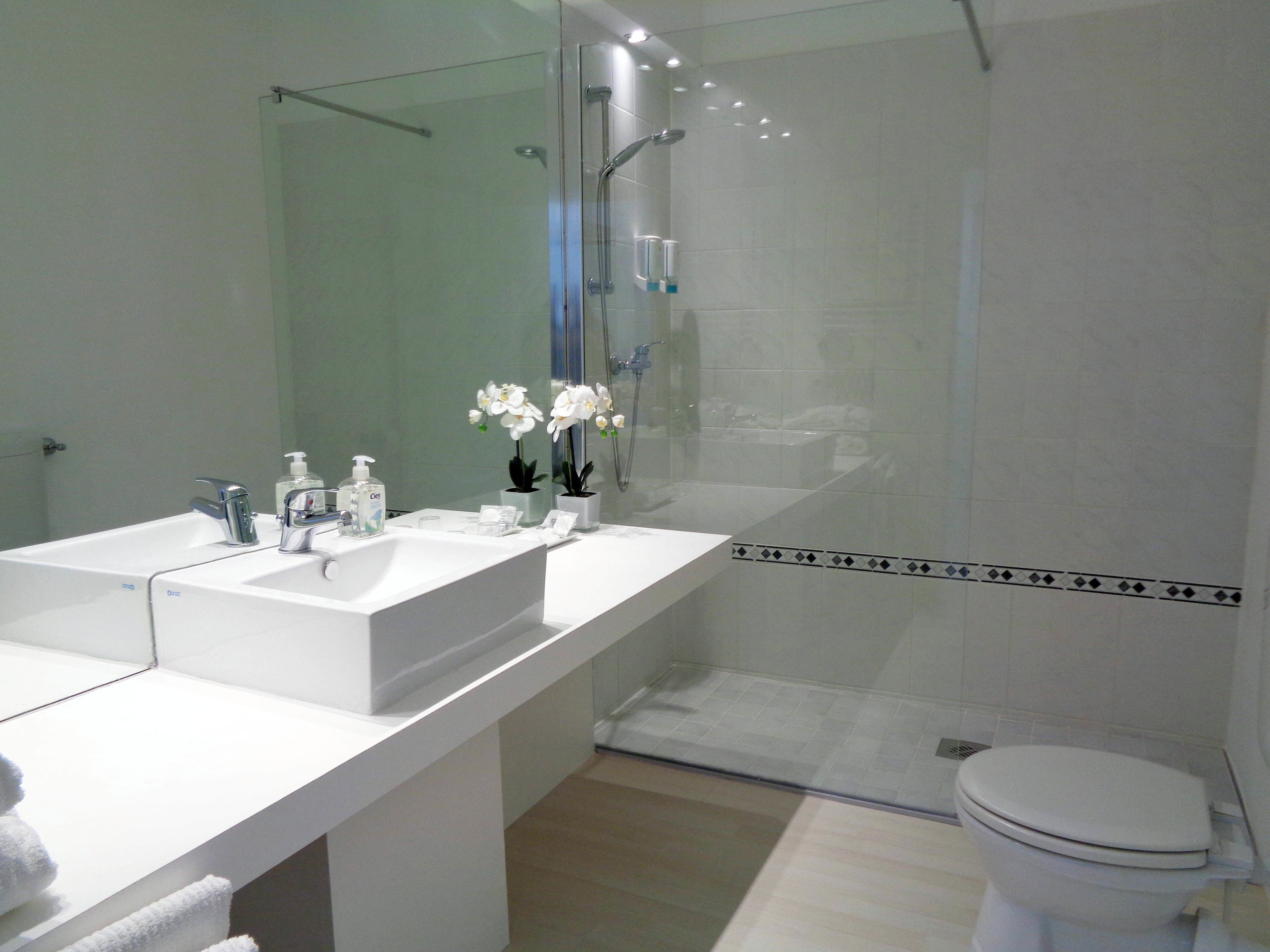 Un baño moderno con lavamanos doble, cabina de ducha de vidrio y retrete.