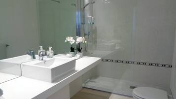 Un baño moderno con lavamanos doble, cabina de ducha de vidrio y retrete.