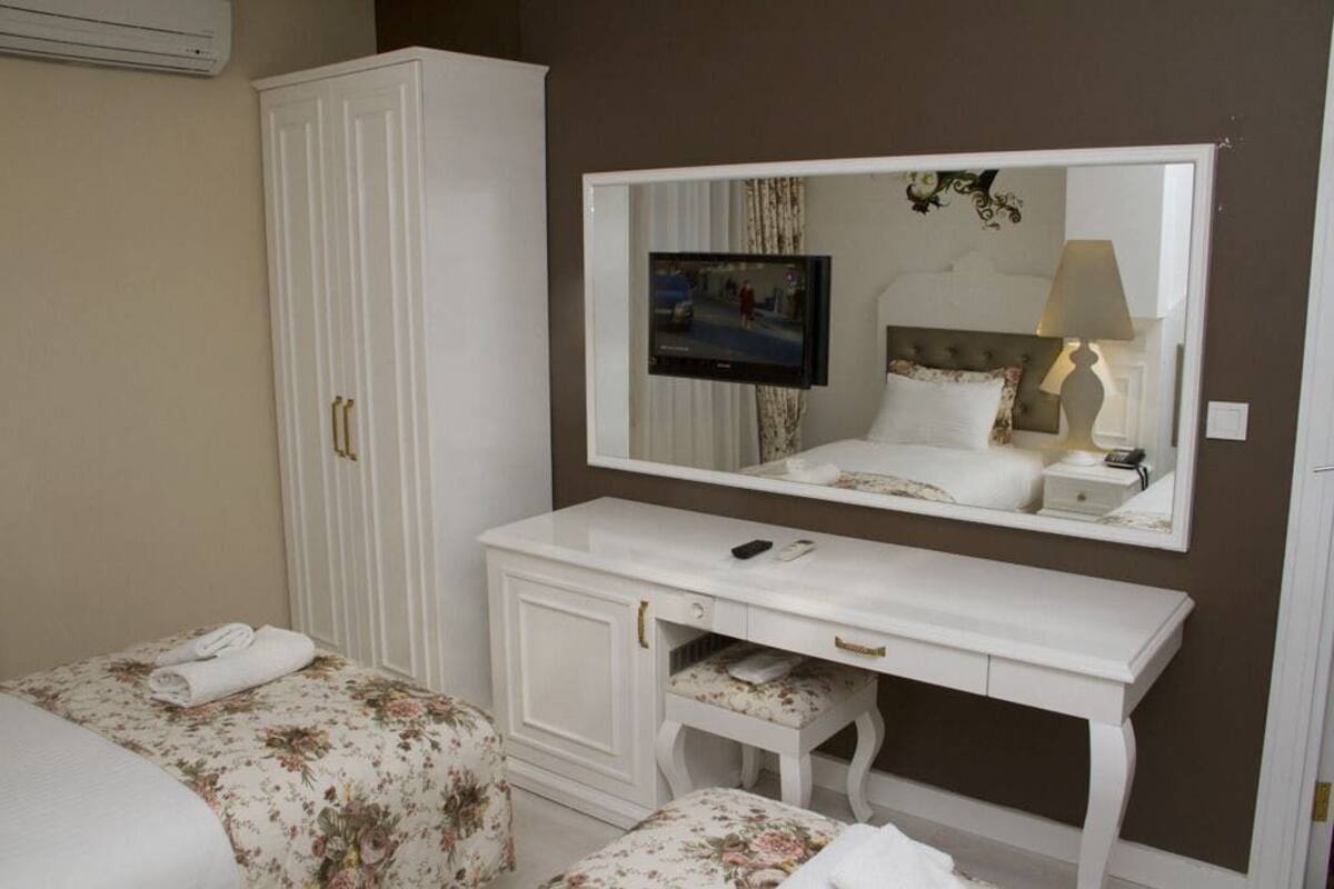 A bedroom with a bed, a dresser, a mirror, and a television.