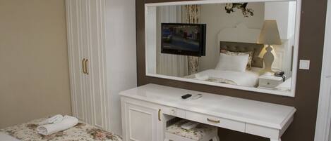 Una camera da letto con un letto, una cassettiera bianca, uno specchio e una televisione.