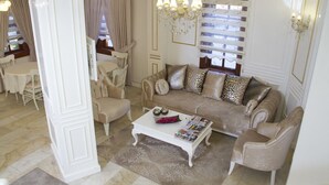 A spacious living room with a beige sofa, matching armchairs, a white coffee table, and a chandelier. - Ozkavak Hotel Kaleici (Antalya)
