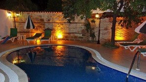 A swimming pool with a stone wall and a thatched roof structure in the background. - Ozkavak Hotel Kaleici (Antalya)