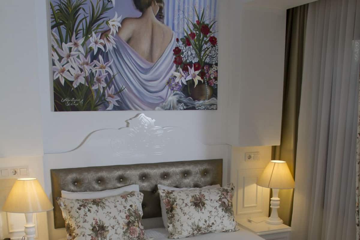 A neatly made bed with floral bedding, a headboard, and two bedside lamps.