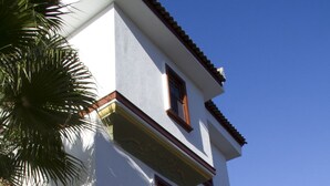 A two-story building with a stone archway entrance, a sign for "ÖZKAVARI SÜTCÜ HOTEL," and a clear blue sky in the background. - Ozkavak Hotel Kaleici (Antalya)