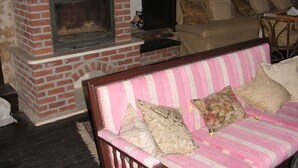 Una sala de estar acogedora con chimenea de ladrillo, sofá a rayas rosas y pared de piedra.