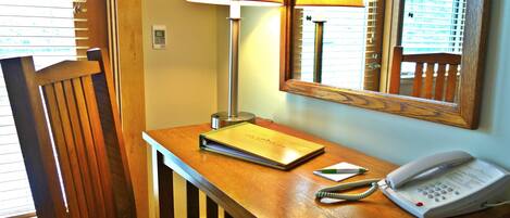A wooden desk with a lamp, a phone, and a notebook.