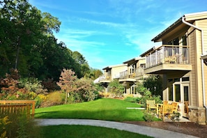 A residential building with a well-maintained lawn, outdoor seating area, and a balcony.