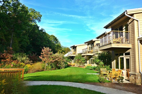 A residential building with a well-maintained lawn, outdoor seating area, and a balcony.