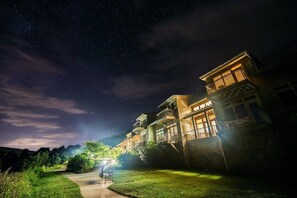 A residential area at night with houses illuminated by streetlights.
