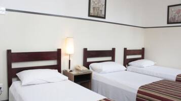 Una habitación de hotel con dos camas individuales, una mesita de noche con una lámpara y un cuadro en la pared.