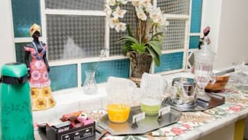 Una encimera de cocina con diversos objetos, incluyendo una licuadora, una jarra y una planta decorativa.