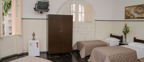 Een hotelkamer met twee bedden, een kledingkast, een televisie en een schilderij aan de muur.
