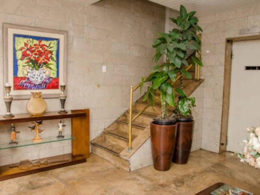 Uma escadaria com guarda-corpo de vidro, um vaso de planta e um vaso em uma mesa de consola.