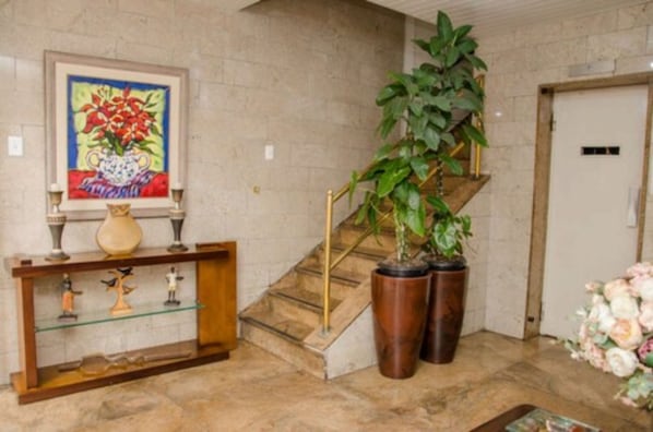 A staircase with a glass railing, a potted plant, and a vase on a console table.