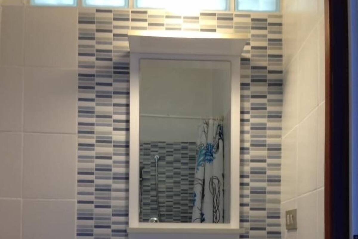 A bathroom with a white sink, a mirror, and a tiled backsplash.