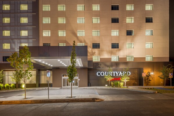 Un hotel Courtyard con una fachada moderna, varios pisos y una entrada bien iluminada.