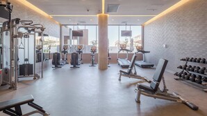 Een sportschool met diverse fitnessapparatuur, waaronder loopbanden, krachtapparaten en gewichten.