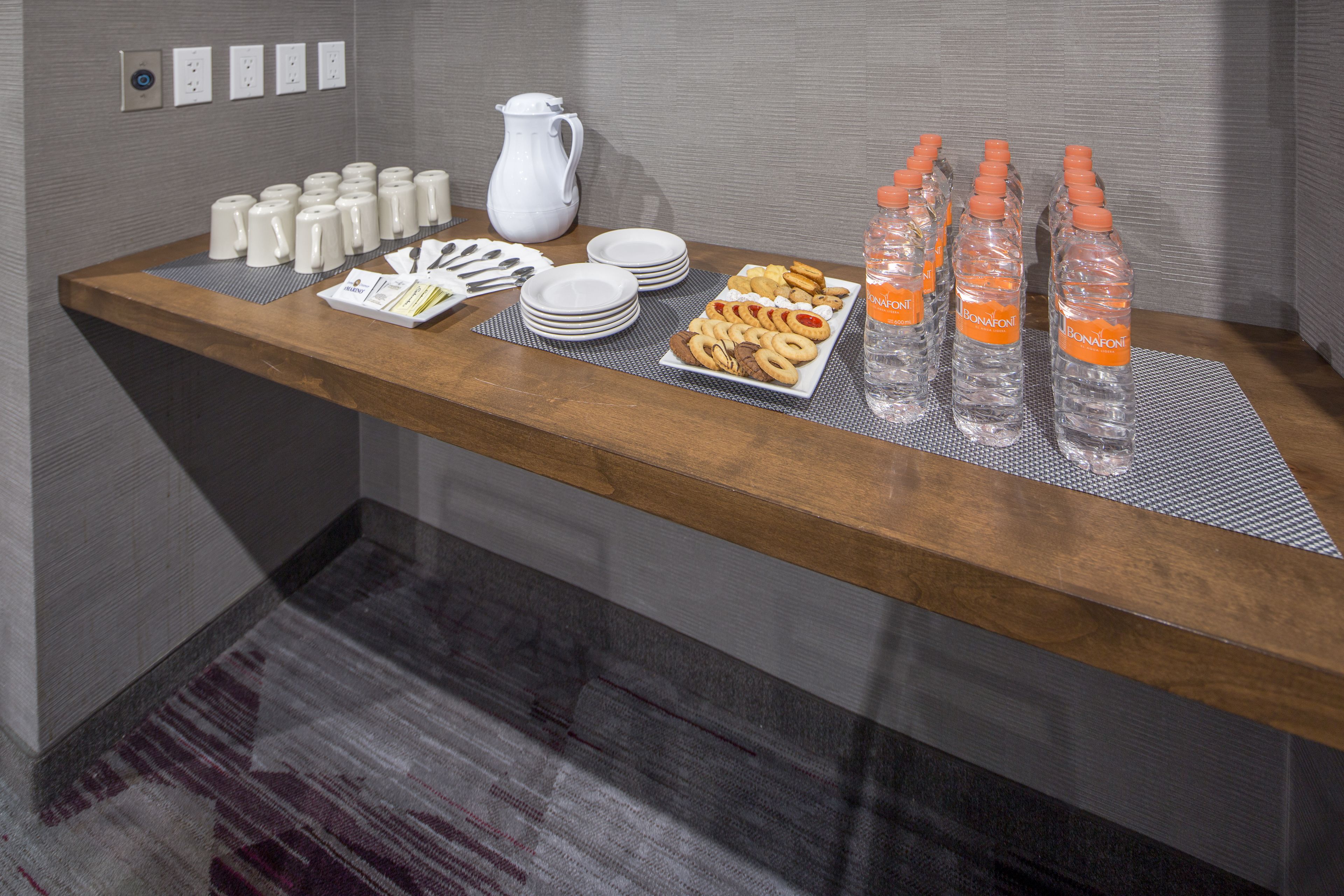 A buffet table with various food items, plates, and water bottles.