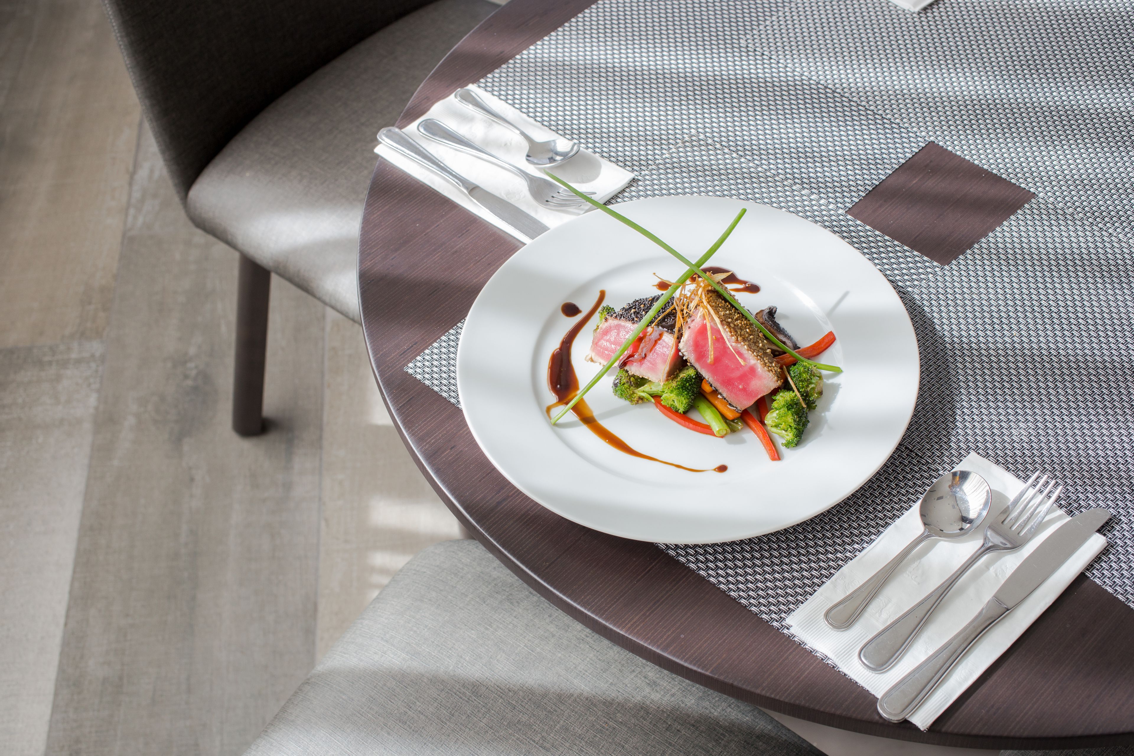 Una mesa de comedor con un plato de comida, cubiertos y una servilleta.