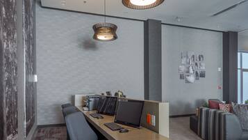 A modern office space with a long wooden desk, multiple computer monitors, and a comfortable seating area with a sofa and a chair.