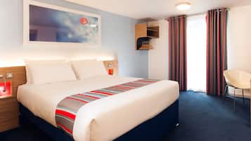 A modern hotel room with a large bed, a bedside table, a chair, and a window with curtains.