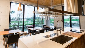 A modern kitchen with a large island, stainless steel appliances, and large windows offering a view of greenery. - Sunrise Bed and Breakfast (Dongshan)