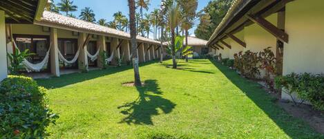 A courtyard with a pool, palm trees, and a building with a tiled roof.