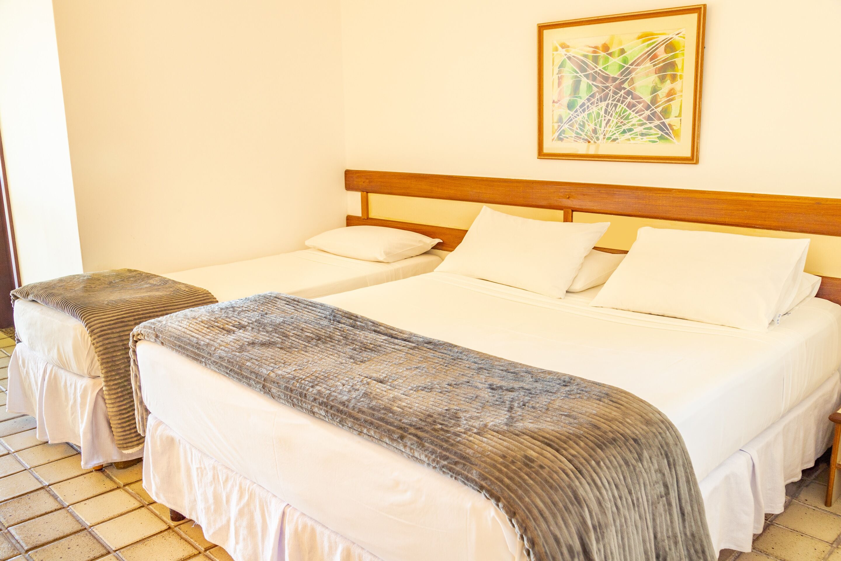 A hotel room with two beds, a wooden headboard, and a painting on the wall.