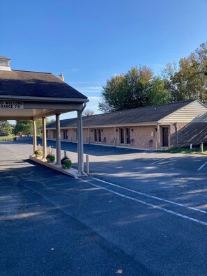 A motel with a covered parking area and a brick building. - Country Squire Inn and Suites (New Holland)