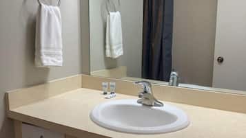Un baño con lavabo, espejo, toallero y cubo de basura.