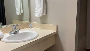 Une salle de bain avec un lavabo blanc, un miroir et deux serviettes suspendues à des porte-serviettes.