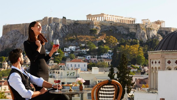 A couple dining at a table with a view of ancient ruins and a church in the background.
