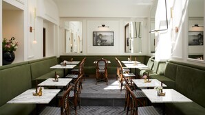 A restaurant with green booths and tables, marble-topped tables, and wooden chairs.