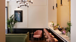 A modern bar area with a wooden floor, green seating, and a bar counter with stools.