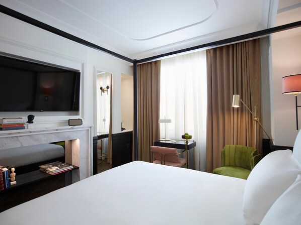 Habitación de hotel con cama, televisión, escritorio con lámpara, silla y sofá.
