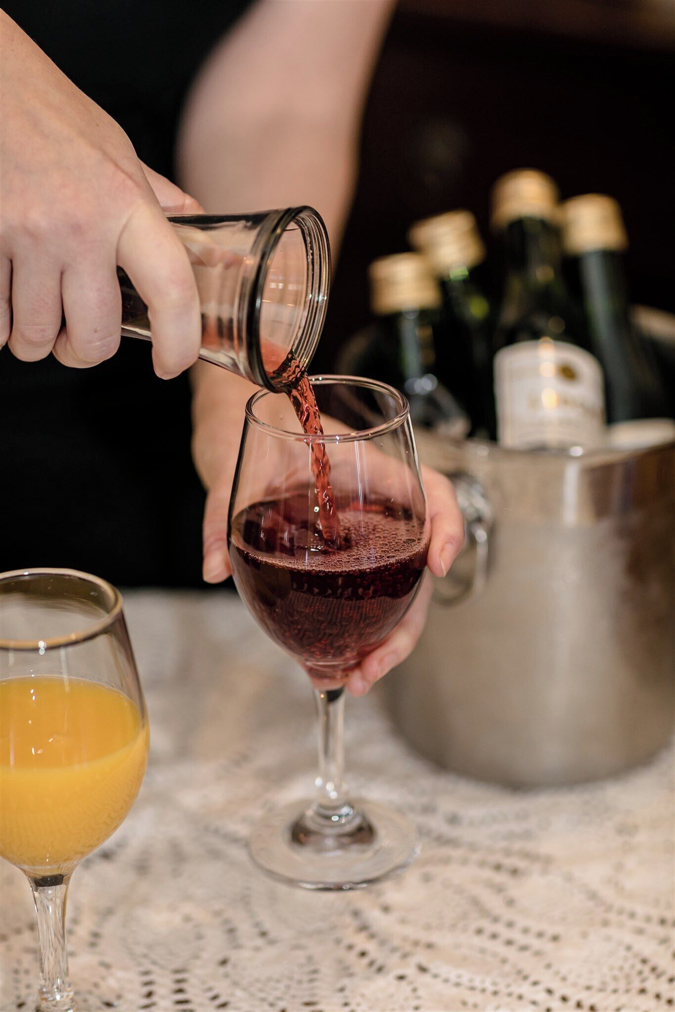 A person pouring a red liquid into a wine glass.