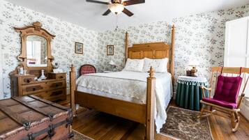 A bedroom with a wooden four-poster bed, a dresser, a chair, and a trunk.
