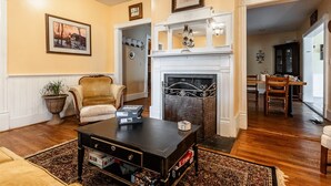 Un salon avec une cheminée, une table basse, un canapé et, au fond, un coin repas.