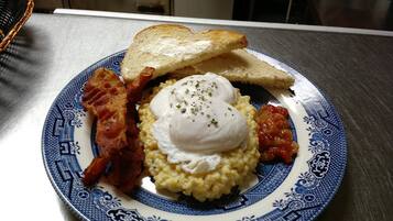 A plate with scrambled eggs, bacon, toast, and tomato sauce.