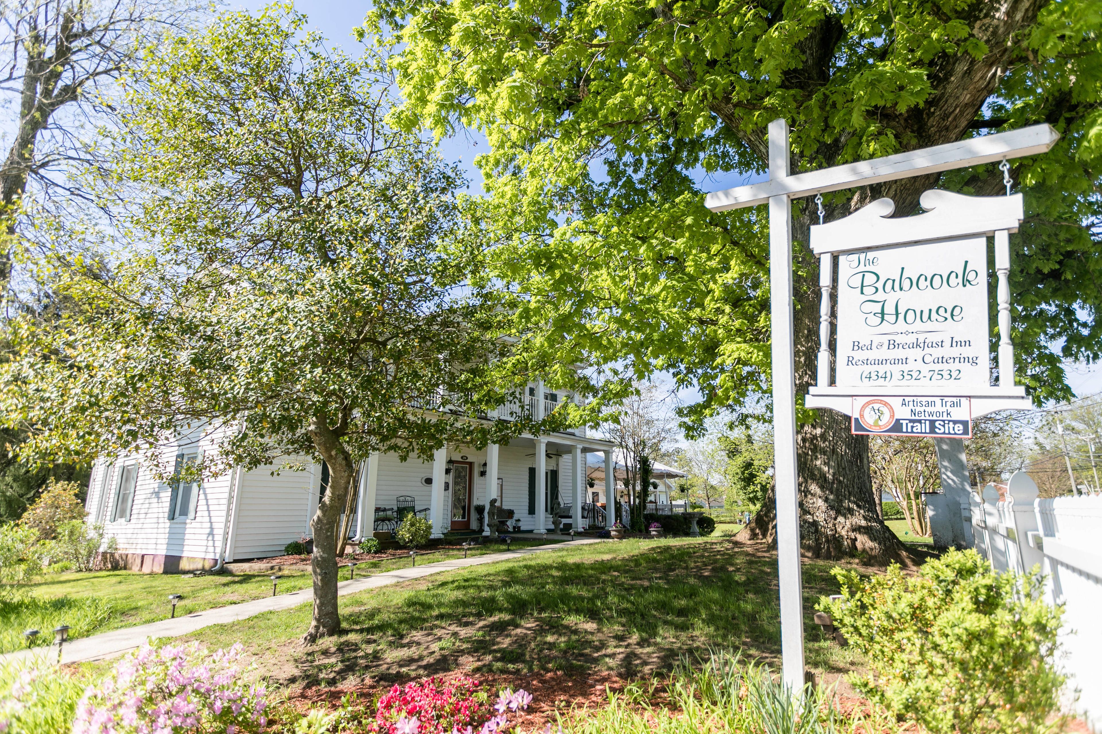 A white house with a porch and a sign for The Babcock House, Bed & Breakfast Inn, Restaurant, and Catering.