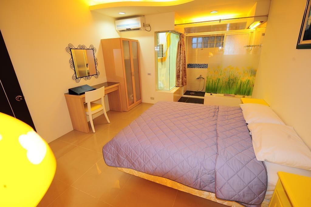 A bedroom with a bed, a desk, a wardrobe, and a shower area.