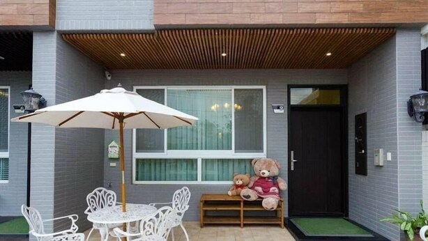 Une terrasse avec une table et des chaises, un banc en bois et deux ours en peluche.