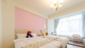 Une chambre avec deux lits, un lustre, une fenêtre avec des rideaux et une chaise.