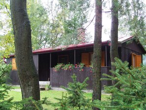 A cabin with a red roof, surrounded by trees and a wooden fence. - Chata Kytlice (Kytlice)