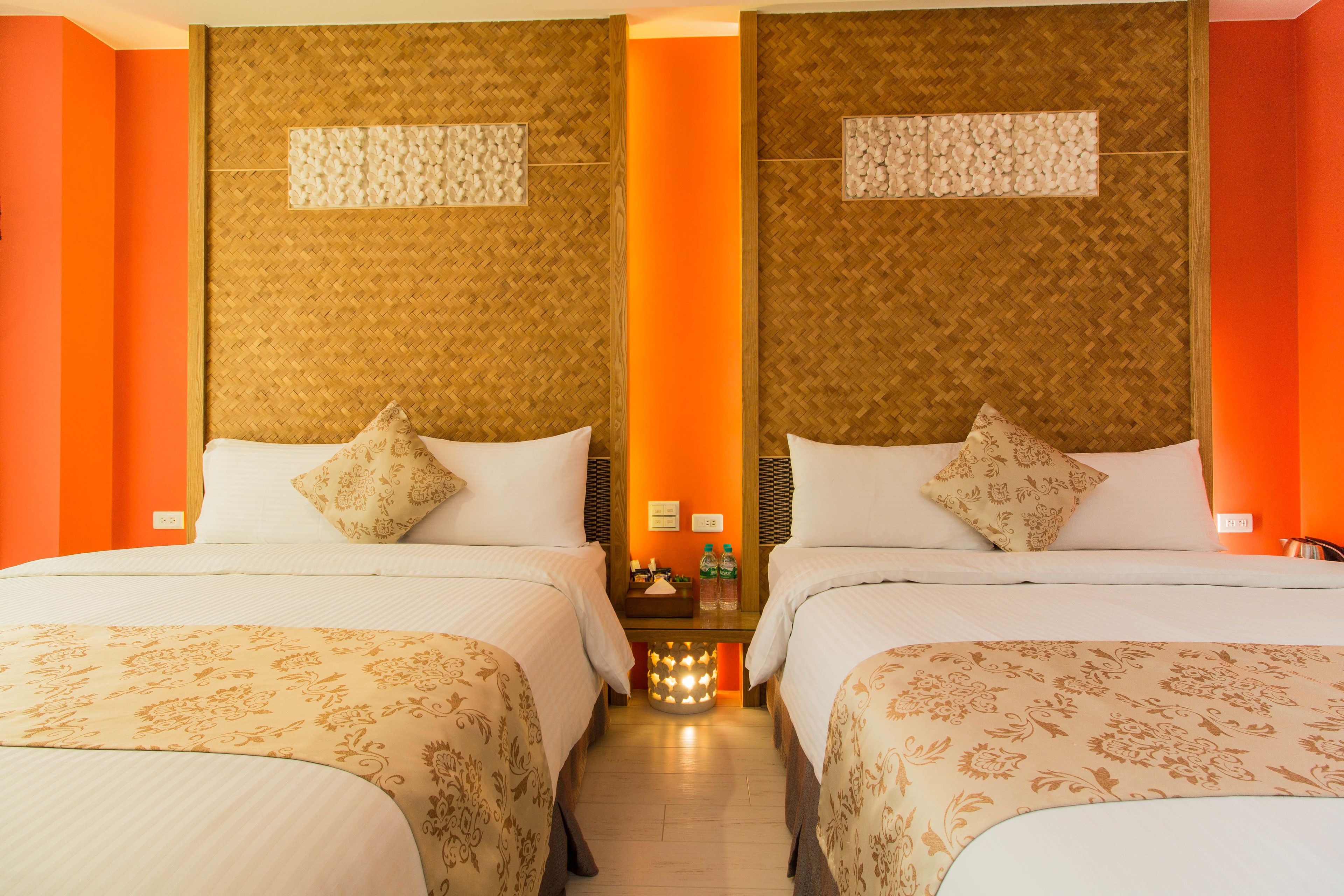 Une chambre d’hôtel avec deux lits, une table de chevet et un luminaire fixé au mur.