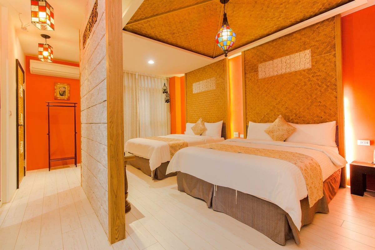 A hotel room with two beds, a wooden ceiling, and a red accent wall.