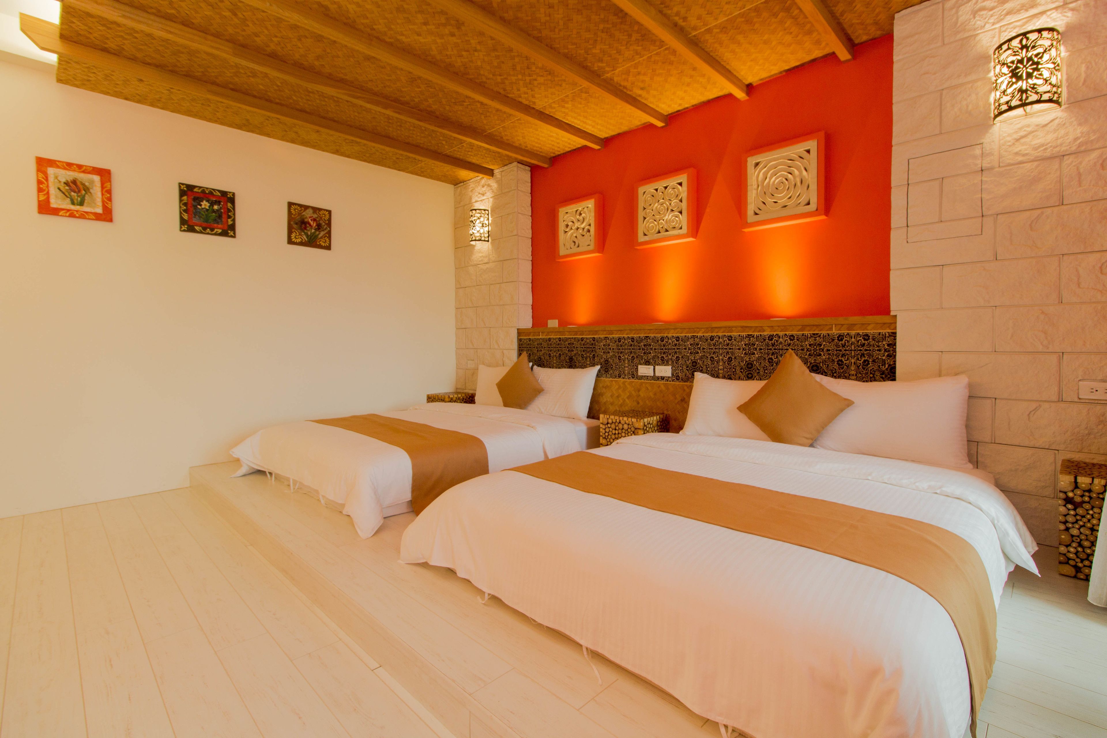 A hotel room with two beds, a red accent wall, and decorative wall sconces.