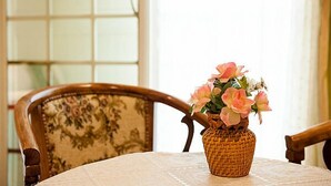 A wicker vase with pink flowers on a table. - Yi Shin Garden Hostel (Shoufeng)