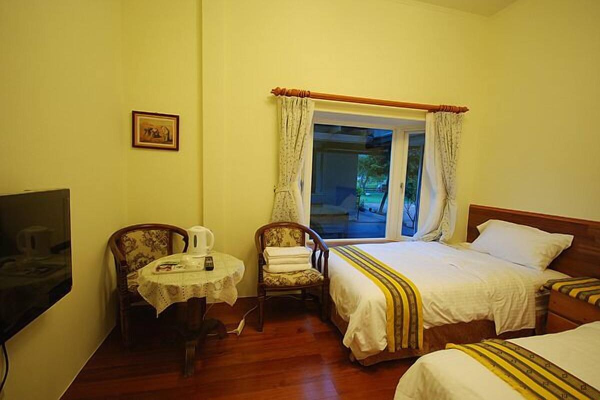 A hotel room with a bed, a chair, a table, and a television.