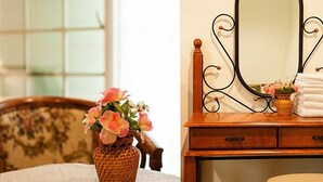 A bedroom with a wooden dresser, a mirror, a vase with flowers, and a bed with a white bedspread. - Yi Shin Garden Hostel (Shoufeng)